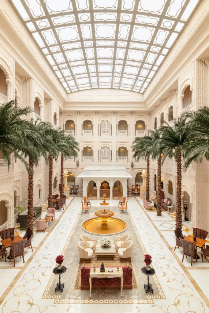 Elegant courtyard at Raffles Jaipur featuring traditional Rajasthani architecture, arches, and warm sandstone tones