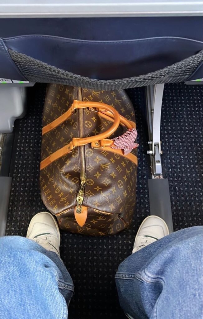  Louis Vuitton Keepall monogram travel bag at an airport, representing luxury travel heritage
